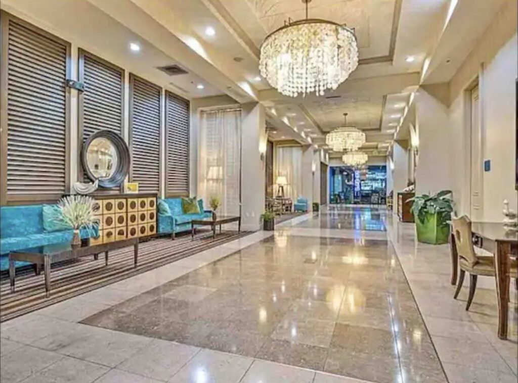 A large lobby with a chandelier and many chairs.