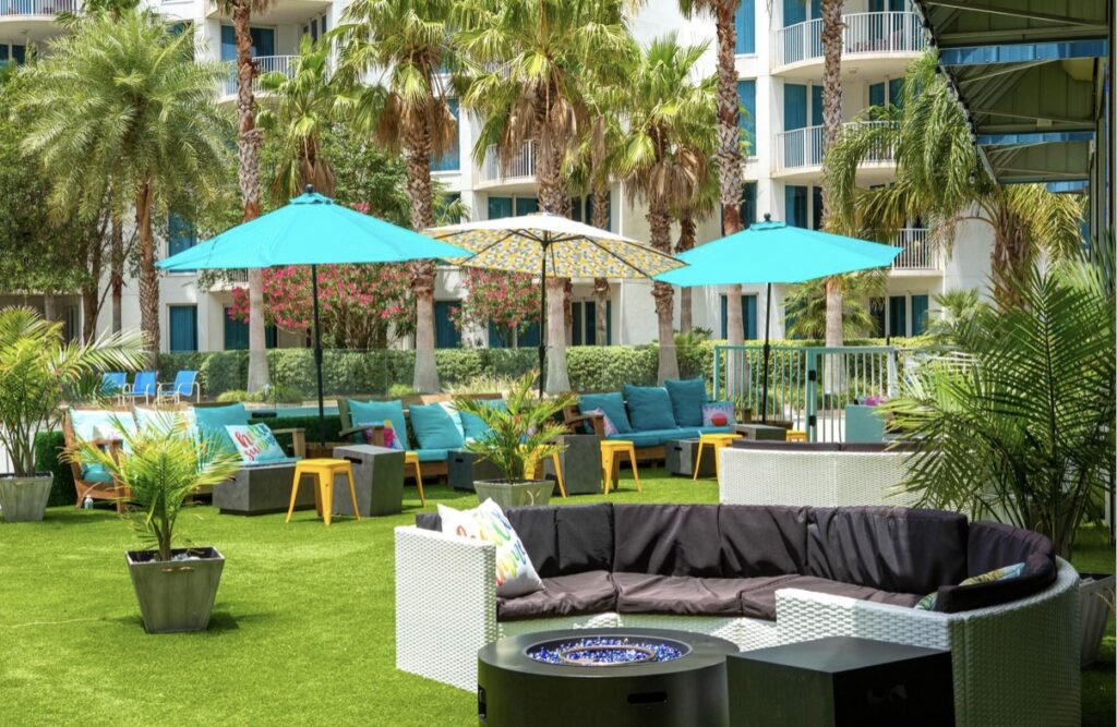 A patio with blue umbrellas and furniture in the middle of it.